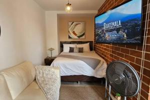 ein Schlafzimmer mit einem Bett und einem TV an einer Backsteinwand in der Unterkunft ¡Torre Modra Apartamento Moderno Atractiva Zona 4! in Guatemala