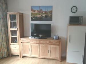 uma televisão num armário de madeira numa sala de estar em Lütje Carolinensiel Harlesiel em Carolinensiel