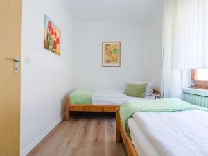 2 Betten in einem Zimmer mit weißen Wänden und Holzböden in der Unterkunft House on the sunny slope type B in Eslohe