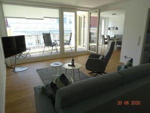 a living room with a couch and chairs and a television at Old Printing House Holiday Apartment Bodoni in Norderney