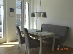 a dining room table with chairs and a bottle of champagne at Old Printing House Holiday Apartment Bodoni in Norderney