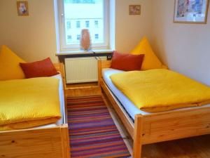 2 Betten in einem Zimmer mit gelber und orangefarbener Bettwäsche in der Unterkunft Vakantieappartement in Berchtesgaden