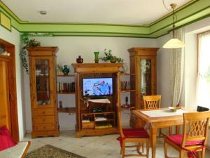 ein Wohnzimmer mit einem TV, einem Tisch und Stühlen in der Unterkunft Holiday apartment 1S oak grove in Lindberg