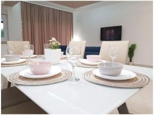 a white table with plates and bowls and wine glasses at Villa Sabun Luxury Villa with Poo, Jacuzzi in Privlaka