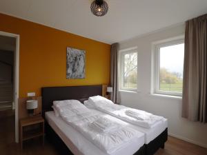 een slaapkamer met een bed met witte lakens en 2 ramen bij Spacious familyhome near the water in Leons