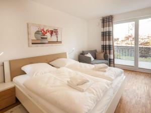 een slaapkamer met 2 witte bedden en een raam bij Dunes Resort Apartment 1 05 in Binz