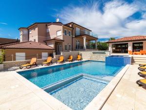 a swimming pool with chairs and a house at Istra Kamen Comfortable holiday residence in Valtura