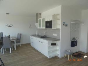 a white kitchen with a sink and a table at Old Printing House Holiday Apartment Cicero in Norderney