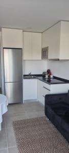 a kitchen with white cabinets and a stainless steel refrigerator at Pensión San Antón in Sanxenxo