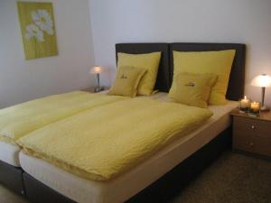 a bedroom with a large bed with yellow sheets and pillows at Krähenberg Country House in Eslohe