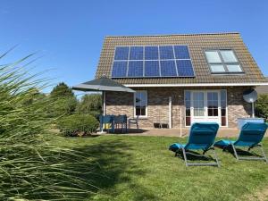 two chairs and an umbrella in front of a house with solar panels at Beachvilla Ijsselmeerblik in Makkum