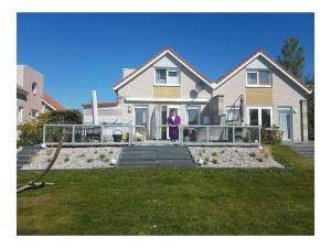 Una mujer parada en el frente de una casa en Villa Sonnenschein, en Makkum
