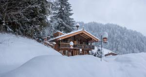 a log cabin in the snow with a pile of snow at Green Chalet from Centuries ago in Reith bei Kitzbühel
