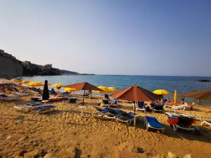 a beach with chairs and umbrellas and the ocean at Suite de la Sicilienne in Castellammare del Golfo