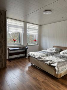 a bedroom with a bed and a desk and two windows at Duc Anh Ferienwohnung in Emden