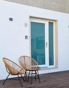 dos sillas sentadas en una terraza junto a una ventana en APARTAMENTOS TURÍSTICOS CASA SANDRA en Sanxenxo