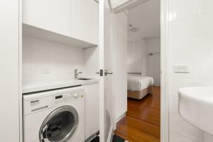 La salle de bains blanche est pourvue d'un lave-linge et d'un lavabo. dans l'établissement Inner-West Studio in a Perfect Location, à Sydney