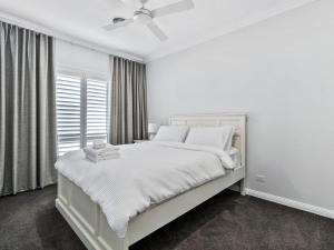 una camera da letto bianca con un letto bianco e una finestra di Hampton Retreat a Yarrawonga Altre 17 foto