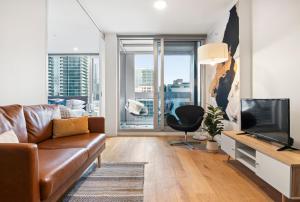een woonkamer met een bank en een televisie bij Skyline Treat Apt in Middle of Shopping Haven in Melbourne