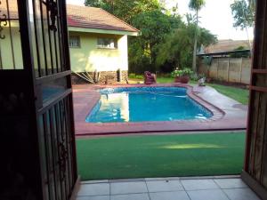une porte ouverte sur une piscine dans une cour dans l'établissement Buffalo Street Cottages, à Malelane 2 autres photos