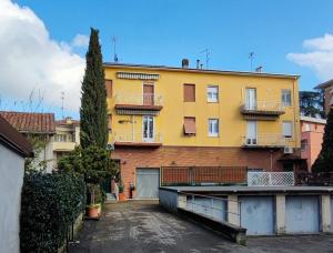 żółty budynek apartamentowy z parkingiem w obiekcie La Porta Verde 8 w mieście Collecchio