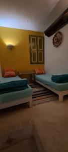 a room with two beds and a yellow wall at Dar fatma medenine in Medenine