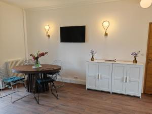 ein Esszimmer mit einem Tisch und einem TV an der Wand in der Unterkunft Domaine de L'isle Maniere in Saint-Quentin-sur-le-Homme