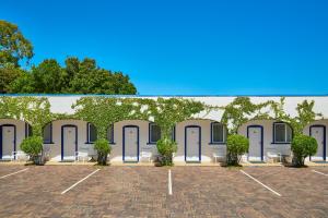 a revestimiento de un edificio con puertas y árboles en The Sails Motel Brunswick Heads en Brunswick Heads