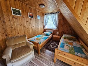 una habitación con 2 camas y una silla en una cabaña en Ferienhaus "BASTEK1" am See mit Kamin & WLAN - Domek Letniskowy BASTEK en Pasym