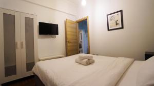 Schlafzimmer mit einem weißen Bett und einem TV an der Wand in der Unterkunft Athens City Themis 7 in Athen