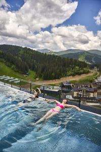 Due donne sdraiate in una piscina su una montagna di Mountain Residence Apartments & Chalet a Bukovel