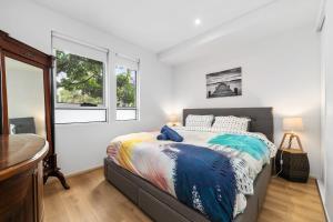 ein Schlafzimmer mit einem Bett und zwei Fenstern in der Unterkunft Port Melbourne Dog Beach Stays in Melbourne
