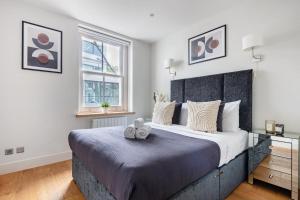 - une chambre avec un grand lit et une fenêtre dans l'établissement 2BR in Soho - Charlotte Street - CityApartmentStay, à Londres