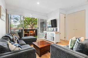 ein Wohnzimmer mit 2 Sofas und einem Tisch in der Unterkunft Port Melbourne Dog Beach Stays in Melbourne