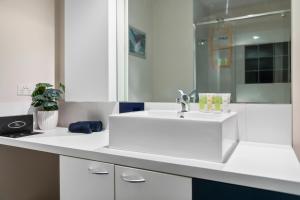 eine weiße Küche mit einem Waschbecken und einem Spiegel in der Unterkunft Port Melbourne Dog Beach Stays in Melbourne
