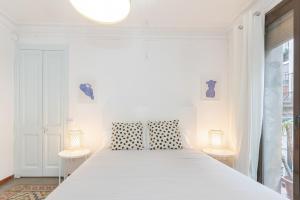 a white bedroom with a large bed with two lamps at VEGUER in Barcelona