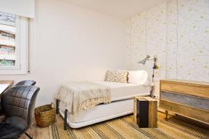 1 dormitorio blanco con 1 cama y 1 silla en LUDERNA - Apartamento Dels tres micos del maresme, en Caldes d'Estrac