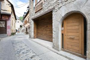 a stone building with two garage doors on a street at LUDERNA - Apartamento Pin Roi in Salardú