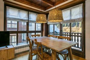a dining room with a table and chairs and windows at Luderna - Apartamento Val de Ruda A14 Montoliu in Baqueira-Beret