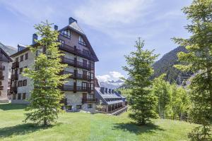 budynek na wzgórzu z drzewami przed nim w obiekcie Luderna - Apartamento Val de Ruda E4 de Marimanha w mieście Baqueira-Beret