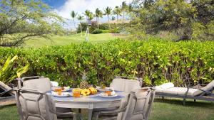 ワイコロアにあるTROPICAL BREEZES Stunning Views from KaMilo 3BR Home Walk to Beachの庭に食べ物と果物を入れたテーブル