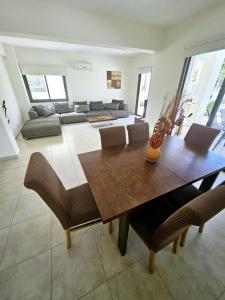 ein Wohnzimmer mit einem Holztisch und Stühlen in der Unterkunft Modern 3 bedroom villa, pool and close to golf course in Paphos City
