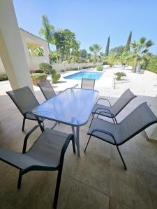a patio with a table and chairs and a pool at Modern 3 bedroom villa, pool and close to golf course in Paphos City