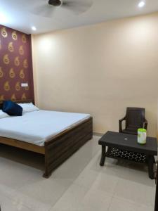 um quarto com uma cama, uma cadeira e uma mesa em Krishna paying guest house em Varanasi