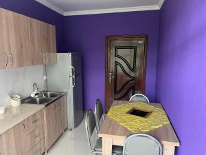 a kitchen with a table with chairs and a purple wall at Garden house in Ambrolauri