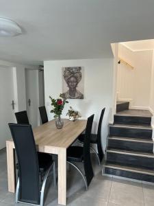 a dining room with a wooden table and black chairs at Maison spacieuse proche Paris in Bonneuil-sur-Marne