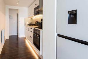 una cocina con armarios blancos y electrodomésticos negros en Stylish Apartment w/ Private Garden - Dog Friendly, en Newport