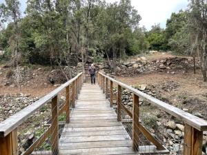 a man walking across a wooden bridge at U FARNIENTE in Patrimonio