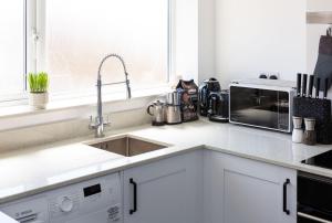a white kitchen with a sink and a microwave at Stylish Duplex Apartment with Home Office in Newport