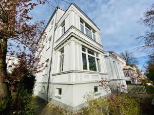 uma grande casa branca com janelas numa rua em Villa Diana/Windrose em Warnemünde